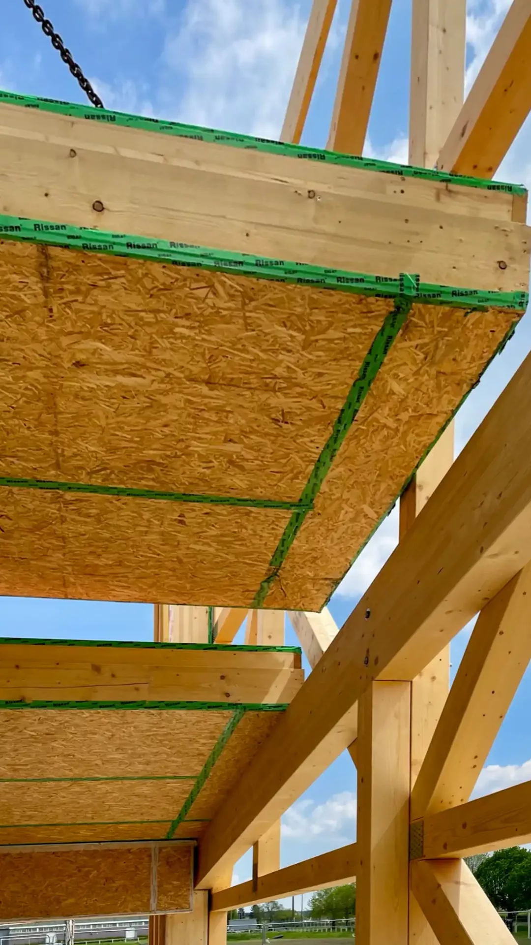 Un caisson isolé en paille est en train d'être placé sur l'armature en bois.